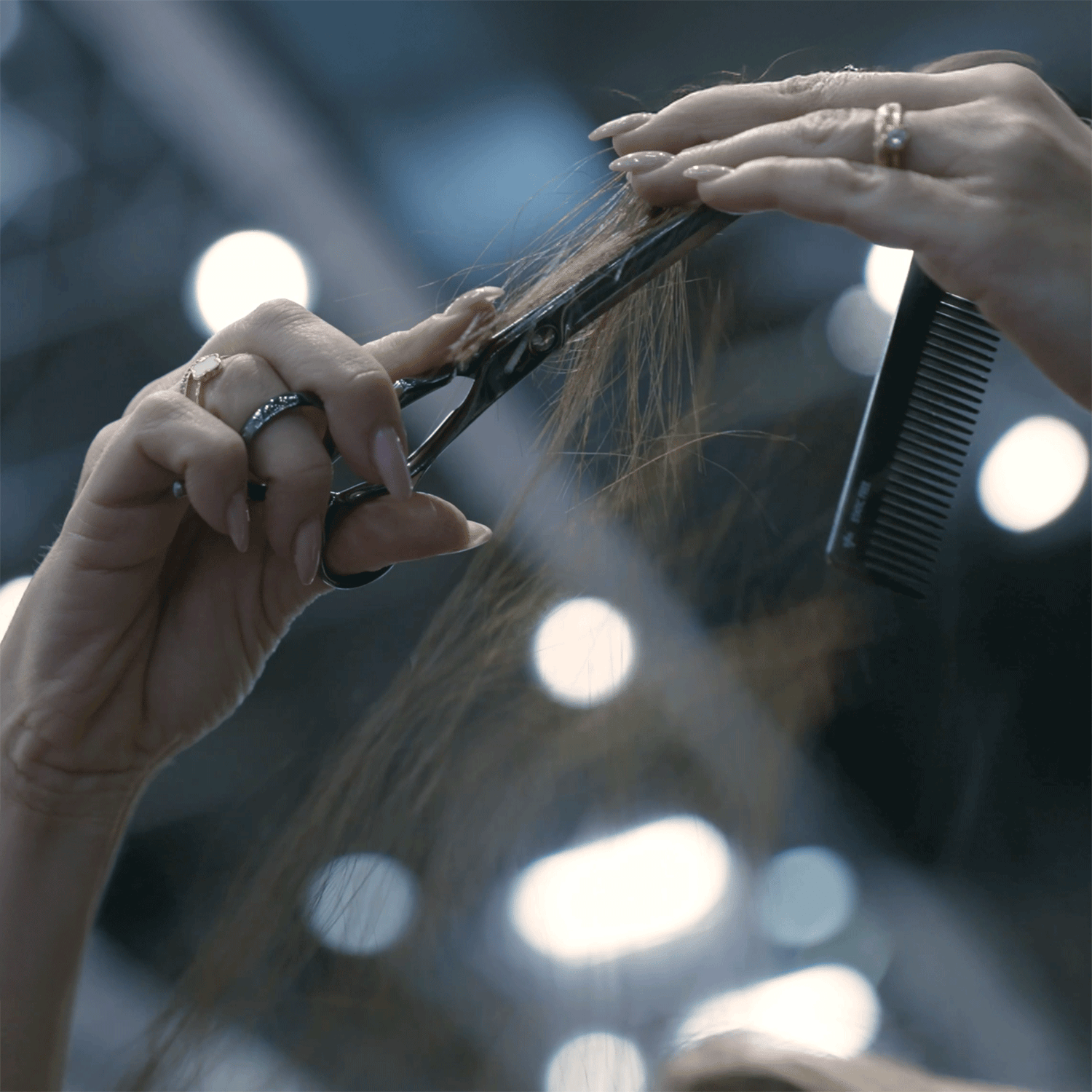 Hairdresser cuts strands of hair with JAGUAR hairdressing scissors and a comb, close-up of the cutting technique.