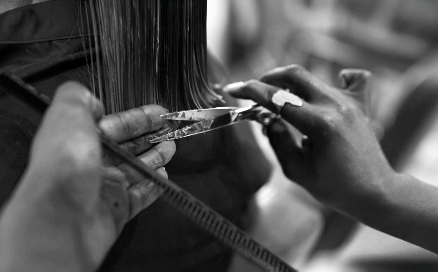 Black-and-white photograph of a precise haircut: hairdresser working ergonomically with JAGUAR hairdressing scissors and comb on hair.