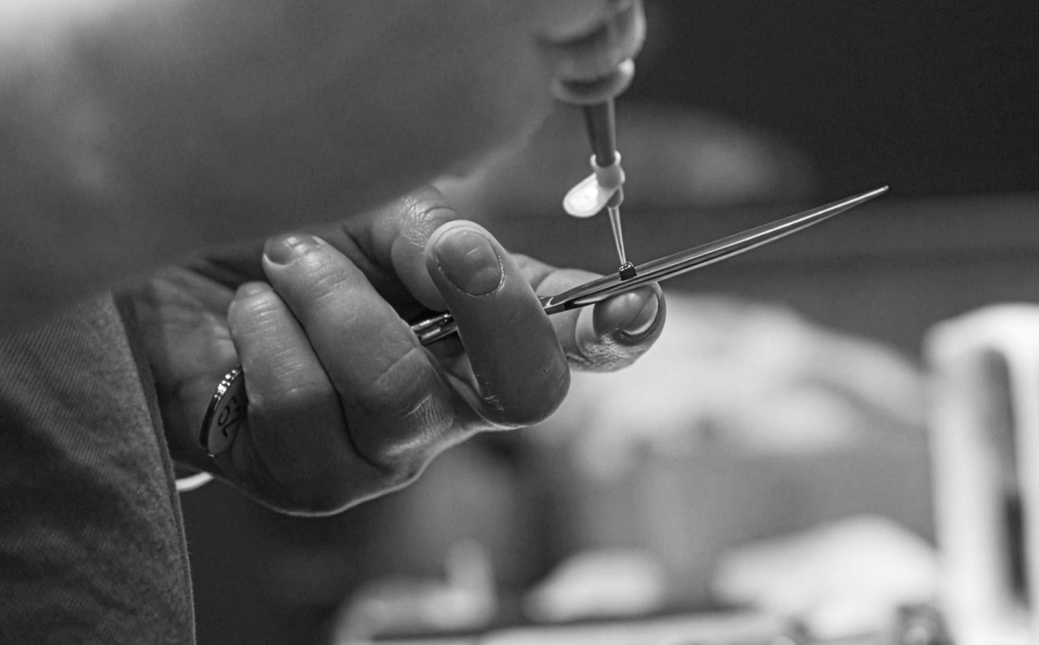 Black-and-white photograph showing the fine adjustment of a JAGUAR hairdressing scissors: adjustment of the screw for optimum smoothness and a precise cutting feel.