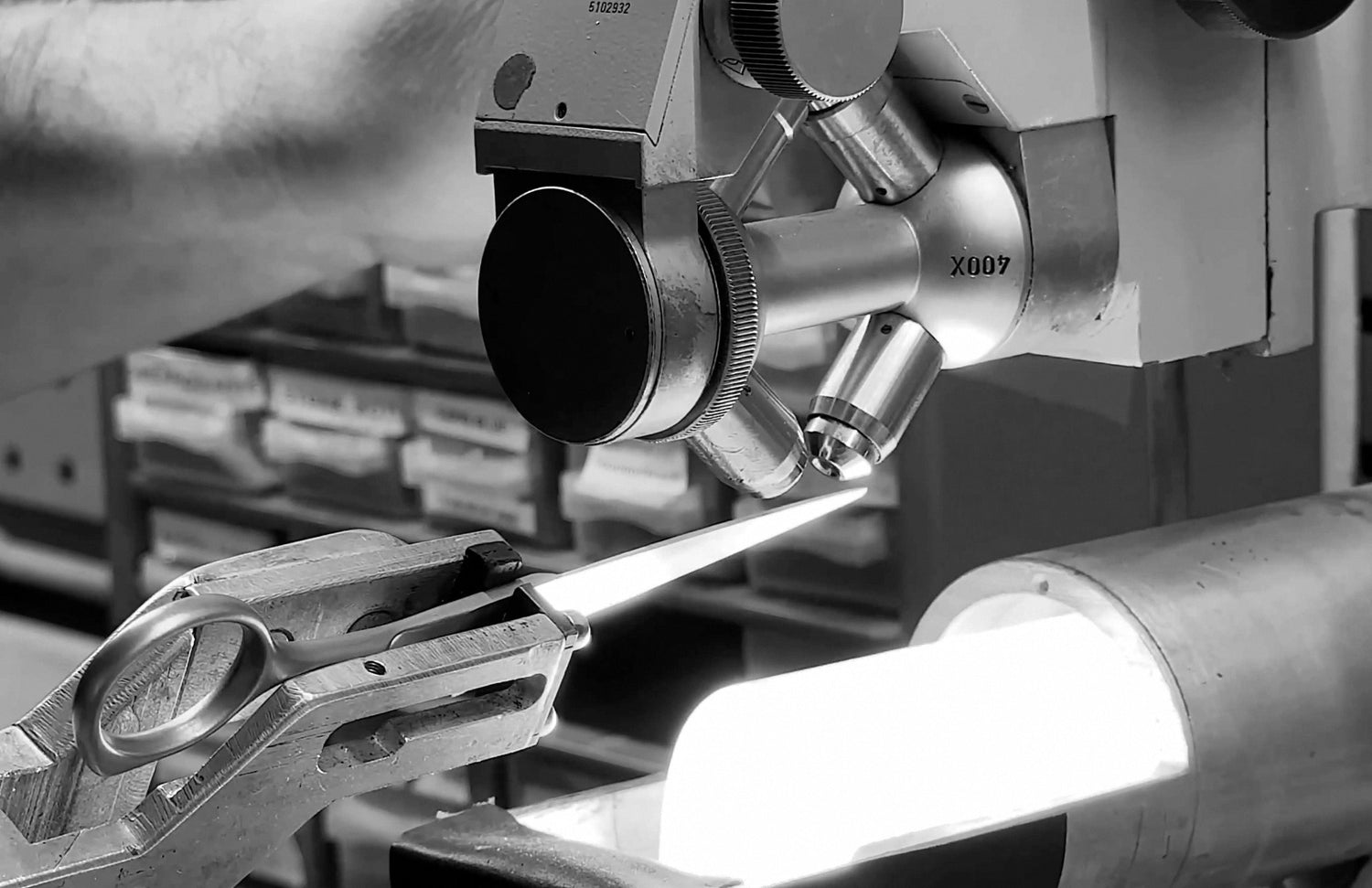 Black-and-white photograph: Precision testing of JAGUAR hairdressing scissors under a microscope at the Solingen production facility.
