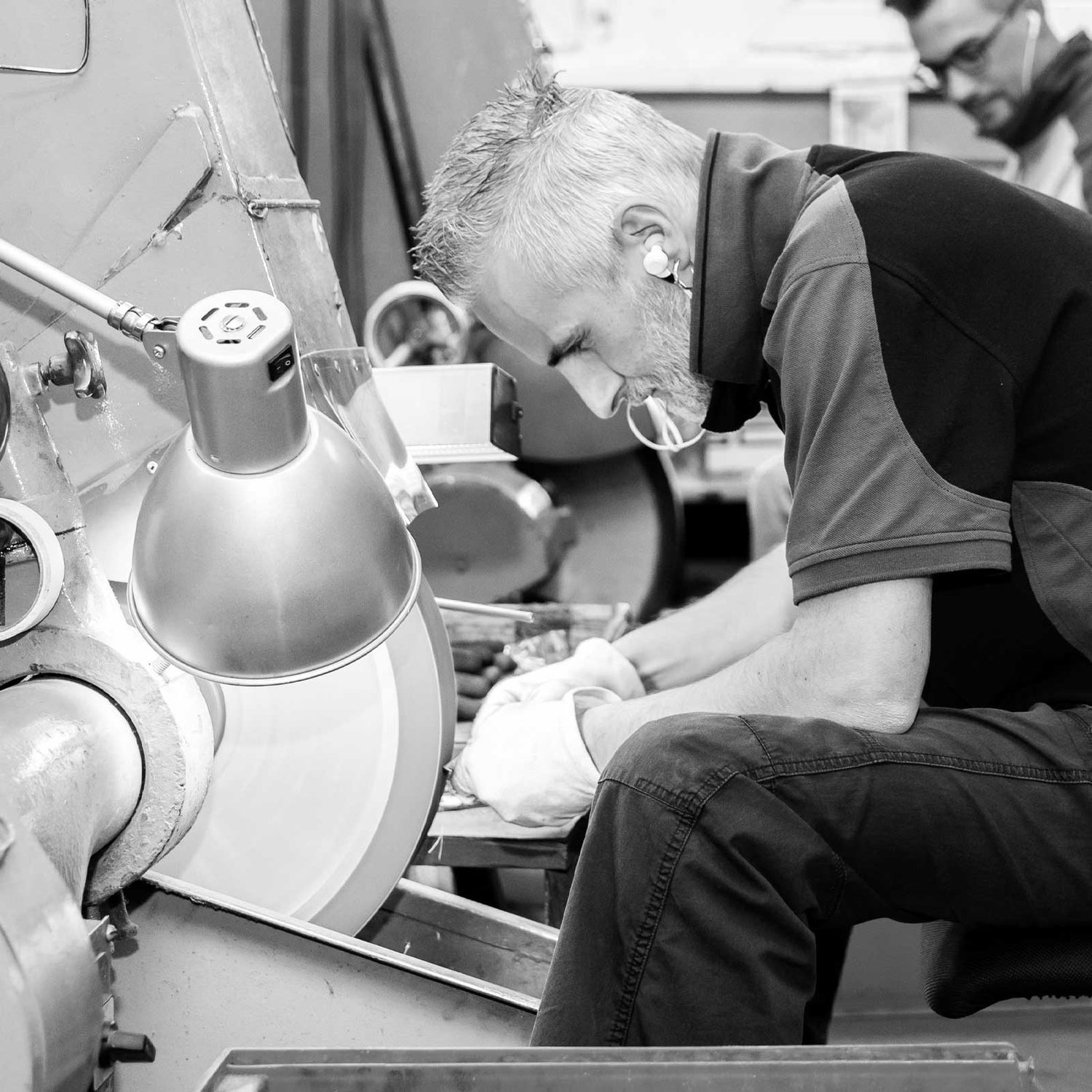 Black-and-white photograph of a JAGUAR employee precision grinding a pair of hairdressing scissors at the Solingen factory.