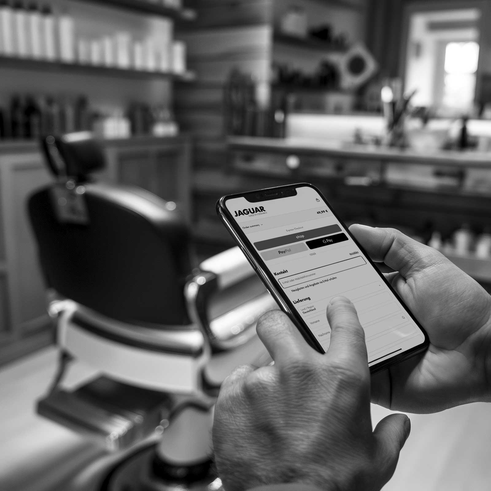 Commande en ligne du service de coupe JAGUAR dans la boutique en ligne via un smartphone – Le coiffeur réserve le service directement depuis le salon.