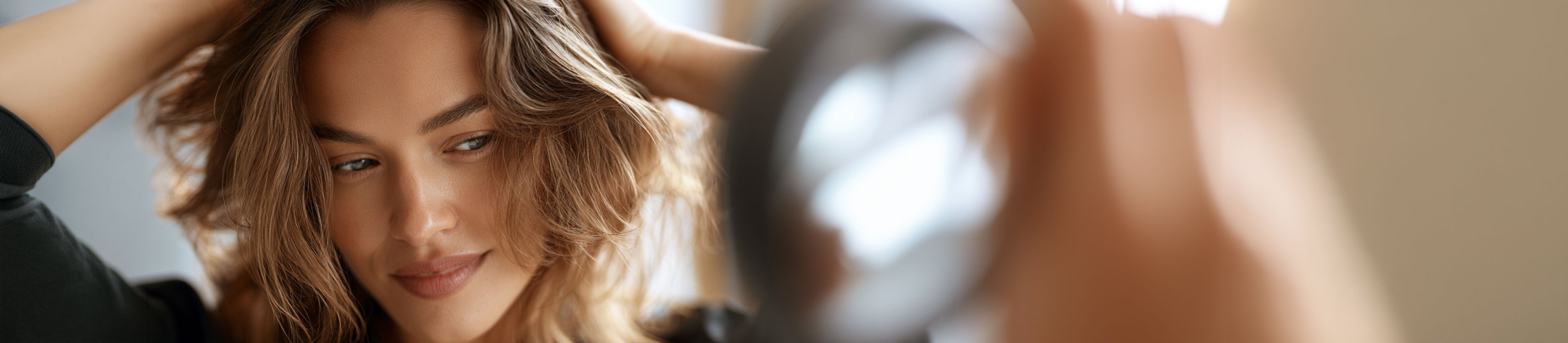 Frau mit gestyltem Haar vor dem Spiegel – professionelle Styling-Ergebnisse für zuhause mit JAGUAR Styling-Tools.