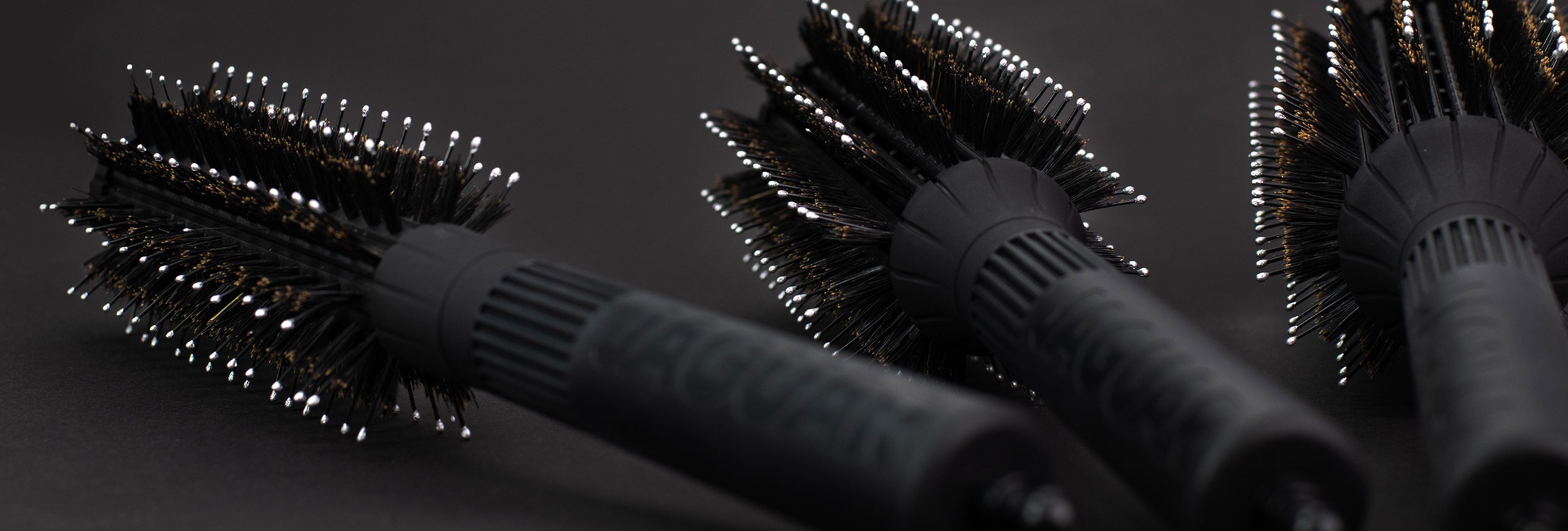 Close-up of JAGUAR T-Boar round brushes with boar bristles on a dark background.