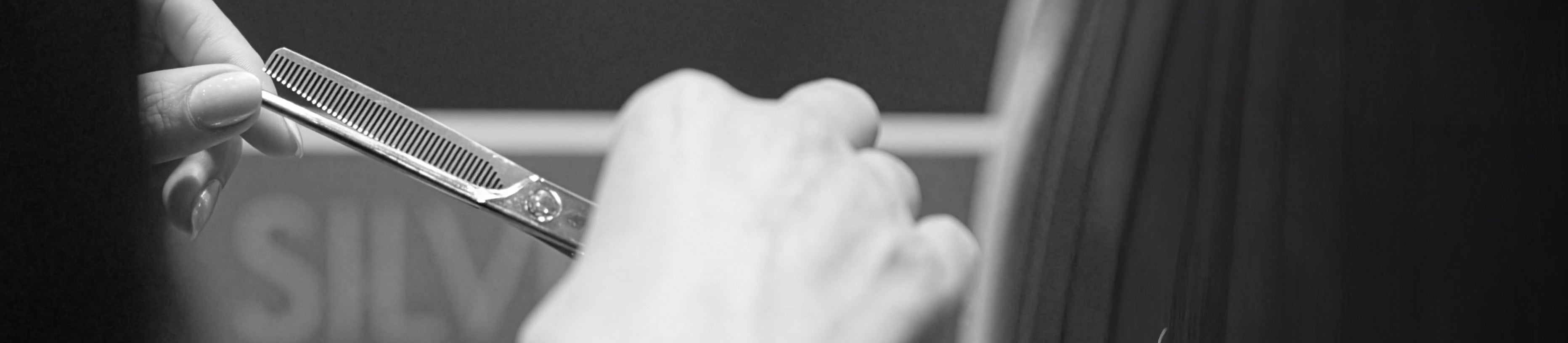 Black-and-white photograph of JAGUAR thinning shears in use – precise thinning of hair strands for controlled texture and clean transitions.