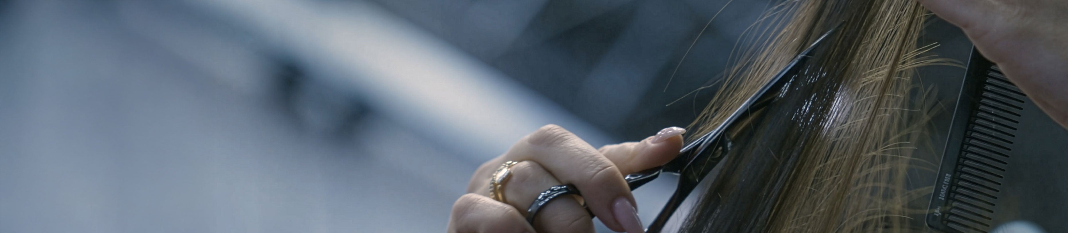 Professional cutting technique in the salon: hairdresser cuts a strand of hair using JAGUAR hairdressing scissors and a comb, focusing on precise cutting, control, and technical expertise.