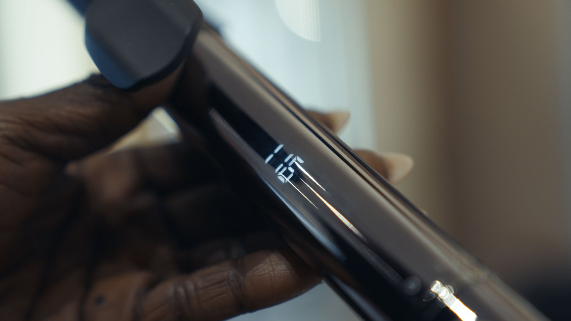 Curling iron with black handle.