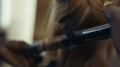 Curling iron with black handle.