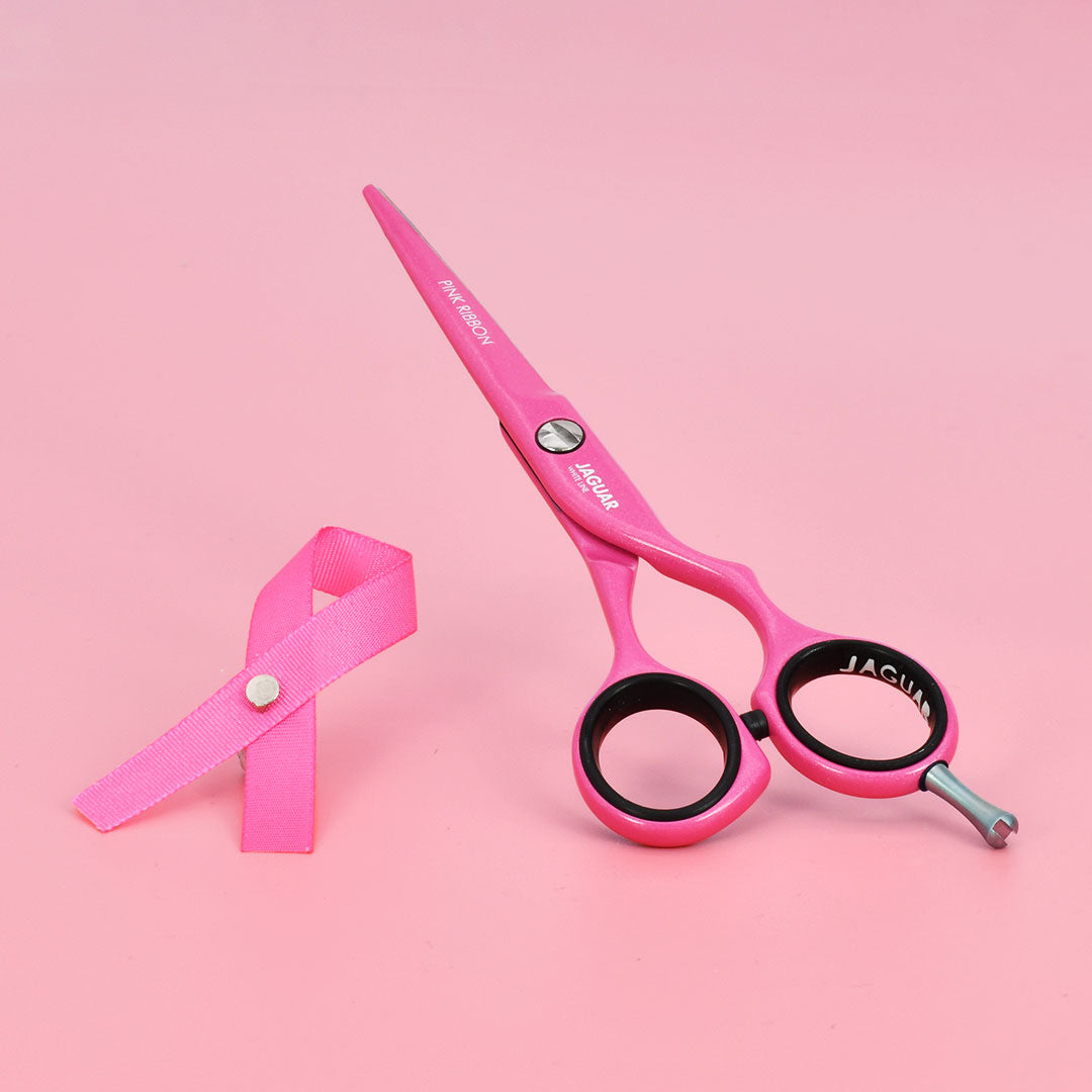 Pink ribbon scissors on a pink background.