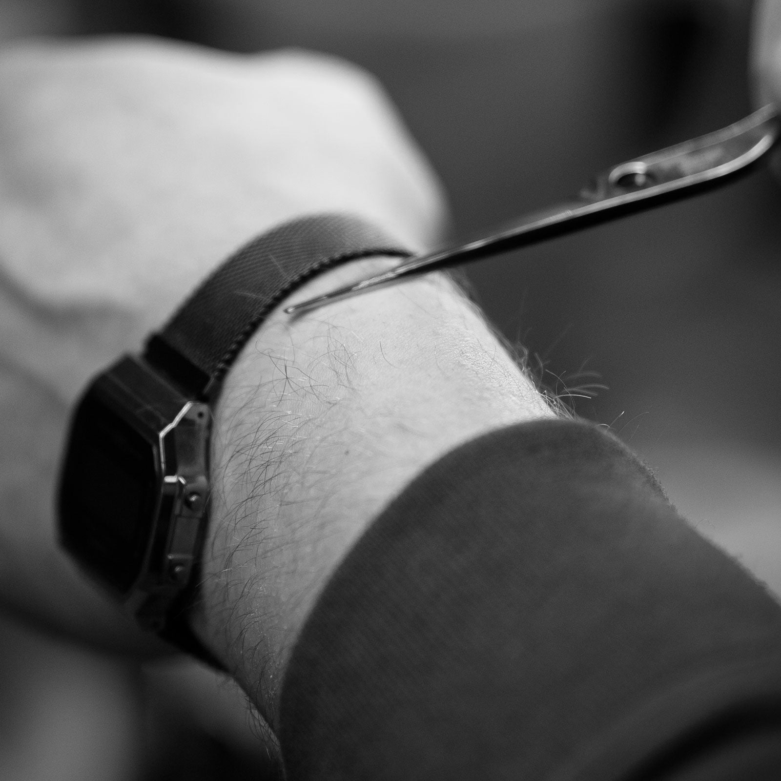 Une paire de ciseaux et un bras en noir et blanc.